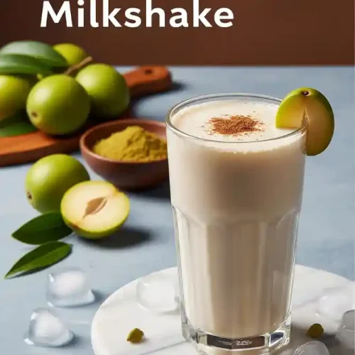 A tall glass of Chikoo Milkshake garnished with a slice, surrounded by fresh chikoo fruits and a bowl of spices on a marble platform, showcasing the rich and creamy texture of the Chikoo Milkshake.