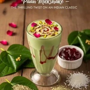 A creamy green Paan Milkshake garnished with nuts and rose petals, sits on a wooden table surrounded by paan leaves, fennel seeds, jam, and coconut.