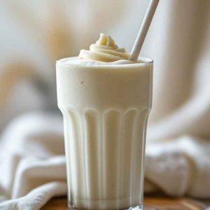 Vanilla Protein Milkshake in a glass, topped with a straw, showcasing a refreshing, protein-packed beverage ready to be enjoyed.