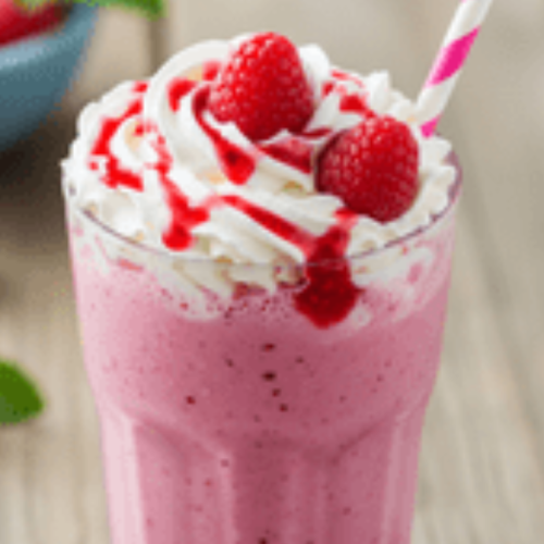 A vibrant raspberry milkshake with a swirl of whipped cream and garnished with strawberries on top.